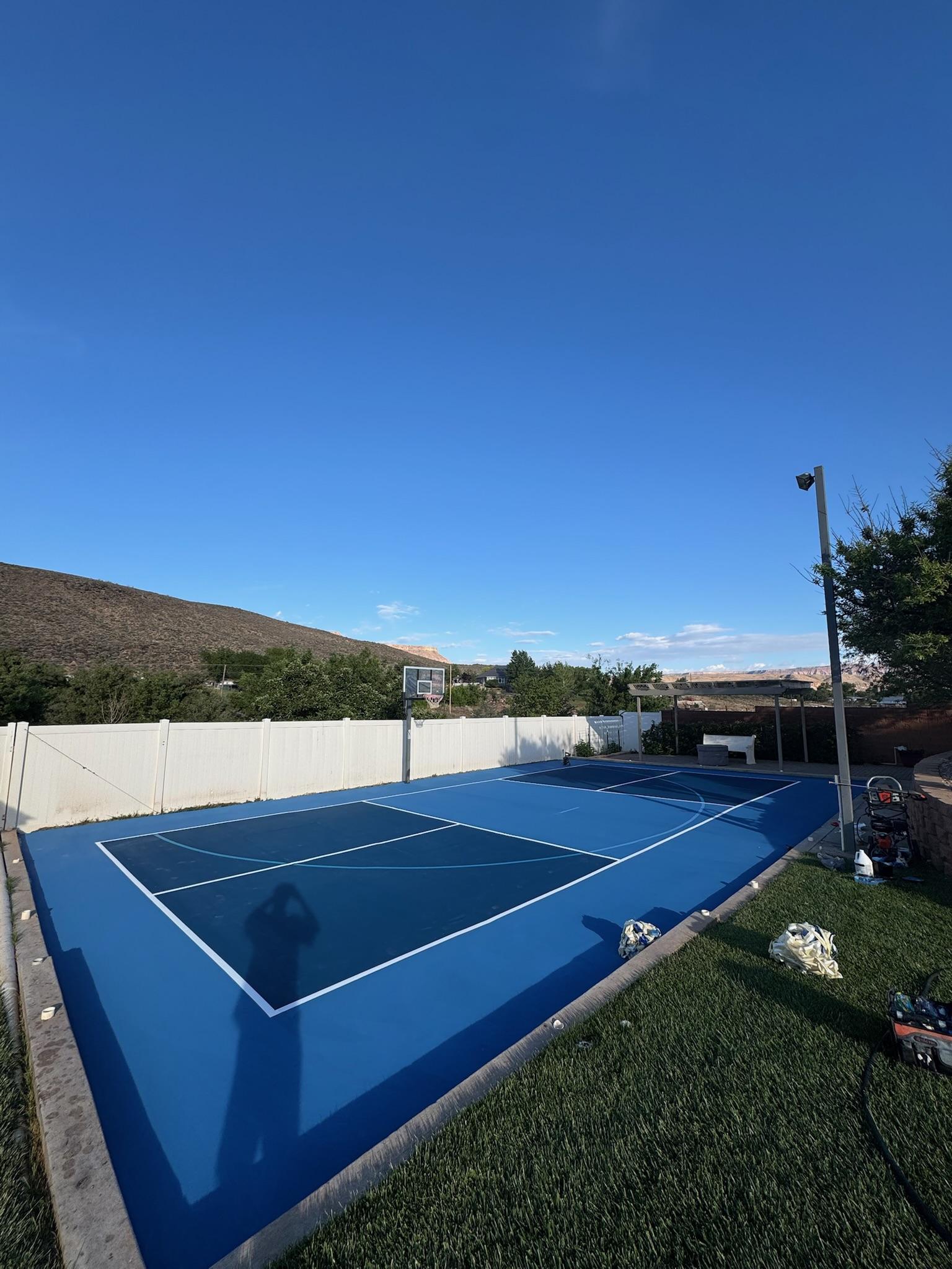Navy and blue multi-sport court with white lines in a desert backyard beneath a red rock hillside