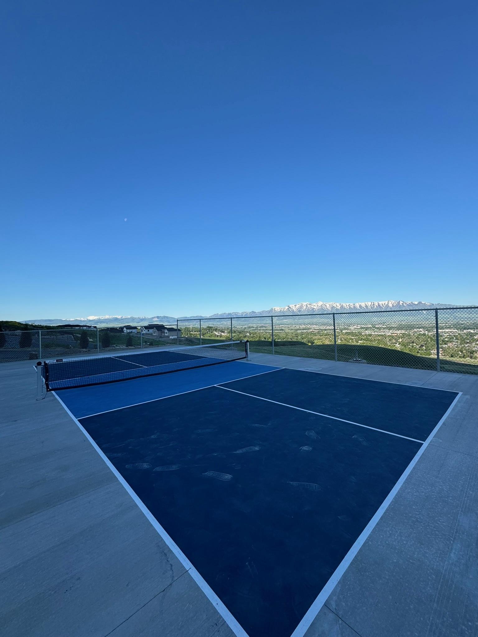 Finished two-tone blue pickleball court on a hilltop overlooking a valley with snow-capped mountains